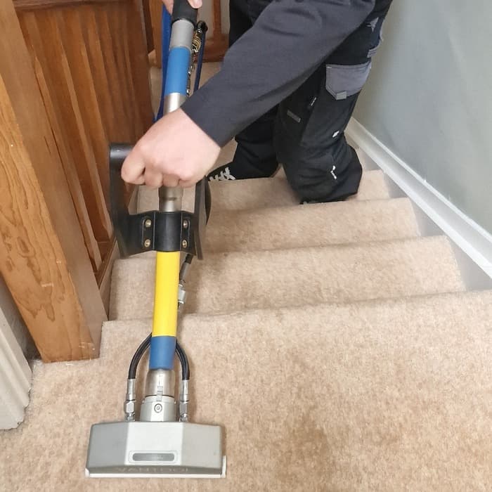 An extraction tool cleaning a carpeted staircase